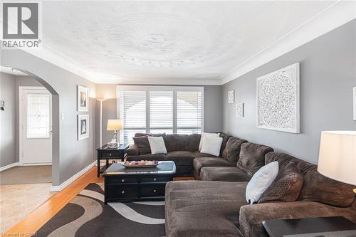 Spacious living area featuring wood-finish flooring, a decorative ceiling, and an arched entryway - 366 Berkindale Drive, Hamilton, ON 