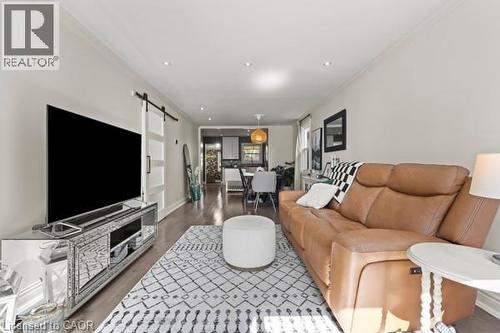 Spacious living area featuring wood-finish flooring, recessed lighting, and a barn door entry - 33 Huxley Avenue N, Hamilton, ON 