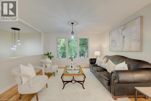 Open-concept living space featuring wood-finish flooring, a contemporary pendant light fixture, and a partial wall divider - 60 Mayfield Avenue, Waterloo, ON 