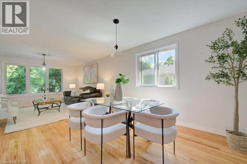 Open-concept room featuring light wood-finish flooring, white walls, and bright natural light from multiple windows - 60 Mayfield Avenue, Waterloo, ON 