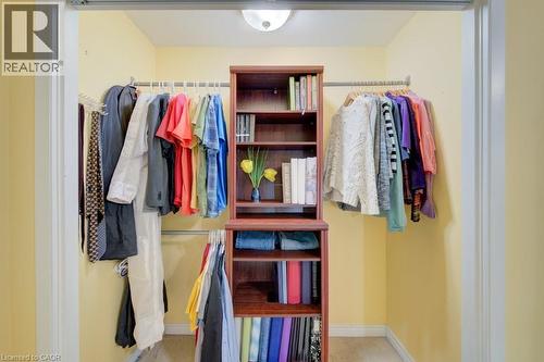 Custom closet organization system featuring a central built-in wood-finish shelving unit - 60 Mayfield Avenue, Waterloo, ON 