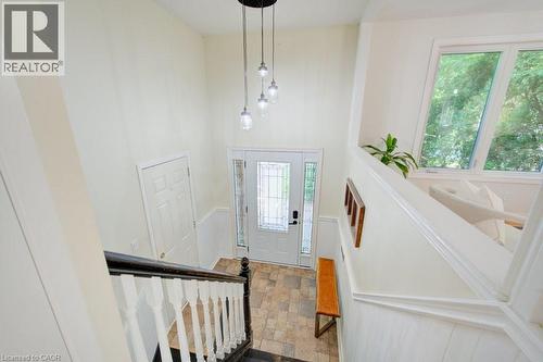 Entryway featuring a multi-light pendant fixture, leaded glass front door, tiled flooring, wainscoting, and large windows - 60 Mayfield Avenue, Waterloo, ON 