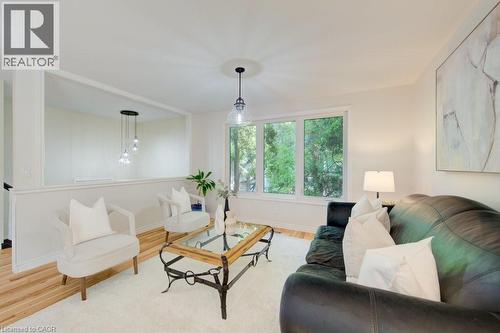 Bright living area featuring a large picture window, wood-finish flooring, and a decorative half-wall partition with a built-in shelf - 60 Mayfield Avenue, Waterloo, ON 