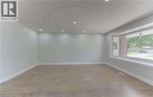 Spacious room featuring wood-finish flooring, a large bay window, recessed ceiling lighting, and a textured ceiling detail - 80 Lower Canada Crescent, Kitchener, ON 