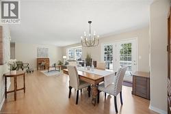 Open-concept living and dining areas featuring light wood-finish flooring, neutral wall tones, a bay window, and double French doors providing direct outdoor access - 