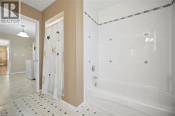 Bathroom featuring a white bathtub, ceramic tile surround with decorative accents, and tiled flooring - 
