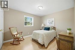 Bedroom featuring wood-finish flooring, a window with blinds, a white ceiling, and neutral-toned walls - 