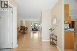 Bright entryway featuring wood-finish flooring, a white paneled door with brass-toned hardware, and neutral-toned walls - 