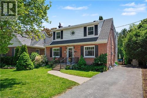 Brick and siding facade featuring a gabled roofline, front entry steps with wrought iron railings, and a paved driveway - 2068 Wellington Avenue, Burlington, ON 