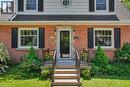 Brick facade residence featuring a front entry porch with stone steps, dark metal railings, and dual exterior wall lanterns - 2068 Wellington Avenue, Burlington, ON 