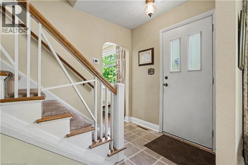 Entryway featuring a staircase with carpeted treads and a wood handrail, ceramic tile flooring, and a door with decorative glass inserts - 2068 Wellington Avenue, Burlington, ON 