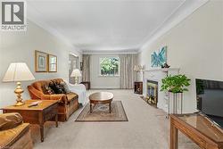 Spacious living area featuring light-toned walls, crown molding, and carpeting - 