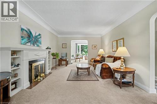 Living area featuring a classic fireplace with a black surround and brass accents, flanked by built-in shelving - 2068 Wellington Avenue, Burlington, ON 