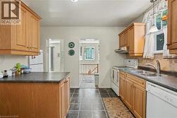 Kitchen featuring wood-finish cabinetry, dark countertops, and slate-finish floor tile - 