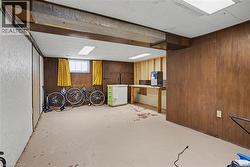 Basement interior featuring wood paneling, exposed ceiling beams, and concrete flooring - 