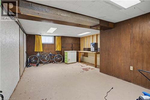 Basement interior featuring wood paneling, exposed ceiling beams, and concrete flooring - 2068 Wellington Avenue, Burlington, ON 