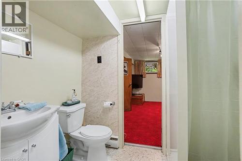 Bathroom featuring a white toilet, white vanity with integrated sink, chrome faucet, and a wall-mounted mirror - 2068 Wellington Avenue, Burlington, ON 