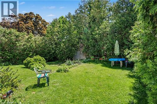 Spacious backyard featuring a lush green lawn, mature perimeter trees, and established shrubbery - 2068 Wellington Avenue, Burlington, ON 
