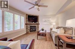Living area with wood-finish flooring and a corner stone-faced fireplace with a wood mantle - 