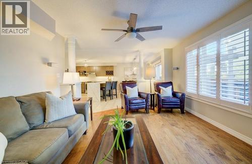 Living area featuring wood-finish flooring, white plantation shutters, a ceiling fan with integrated lighting, and crown molding - 7 Housler Lane, Cambridge, ON 