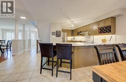 Kitchen featuring wood-finish cabinetry, stainless steel appliances, a white tile backsplash, and a central island with countertop seating - 