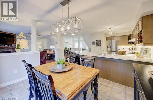 Tiled flooring extending into the kitchen with a large central island, stainless steel refrigerator, and upper and lower cabinetry - 7 Housler Lane, Cambridge, ON 