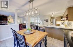 Tiled flooring extending into the kitchen with a large central island, stainless steel refrigerator, and upper and lower cabinetry - 