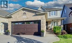Front exterior featuring a combination of brick and siding, a two-car garage with a panel door, and a covered porch with decorative columns - 