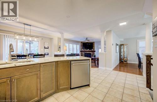 Spacious open-concept interior featuring light-toned tile flooring, a kitchen island with integrated sink, stainless steel dishwasher, and recessed lighting - 7 Housler Lane, Cambridge, ON 