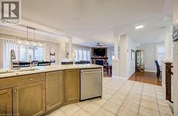 Spacious open-concept interior featuring light-toned tile flooring, a kitchen island with integrated sink, stainless steel dishwasher, and recessed lighting - 