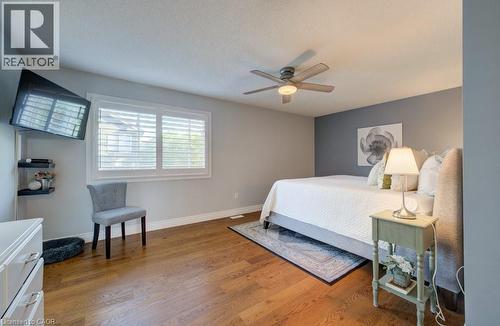 Spacious room featuring wood-finish flooring, a ceiling fan with integrated lighting, and a window with white louvered shutters - 7 Housler Lane, Cambridge, ON 