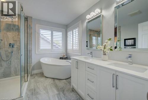 Spacious bathroom featuring a freestanding soaking tub, a glass-enclosed shower with a rainfall showerhead, and a double vanity with ample storage - 7 Housler Lane, Cambridge, ON 