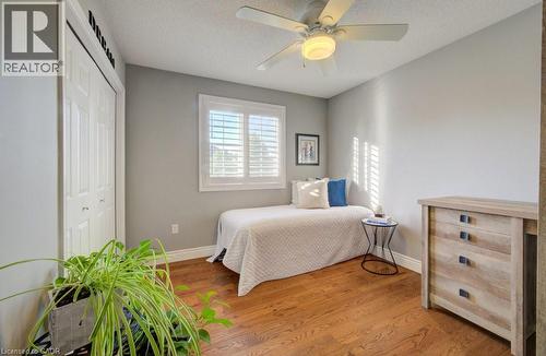 Interior space featuring wood-finish flooring, a ceiling fan with light fixture, and a window with plantation shutters - 7 Housler Lane, Cambridge, ON 