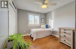 Interior space featuring wood-finish flooring, a ceiling fan with light fixture, and a window with plantation shutters - 