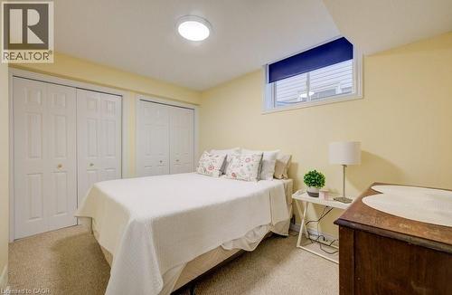 Carpeted room featuring a white bi-fold closet, additional bi-fold closet, and a horizontal window with a blue roller shade - 7 Housler Lane, Cambridge, ON 