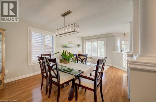 Dining area featuring wood-finish flooring, white plantation shutters, and a rectangular chandelier - 7 Housler Lane, Cambridge, ON 