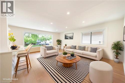 Bright living area featuring wood-finish flooring, recessed lighting, a wide picture window, and a breakfast bar with a solid surface countertop - 22 Charlotte Crescent, Kitchener, ON 