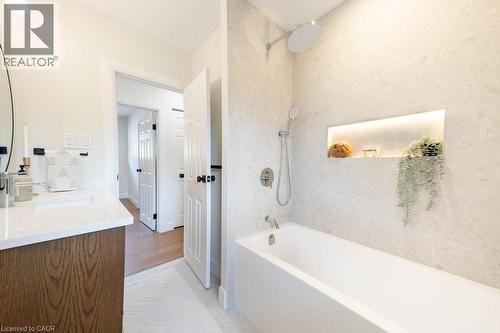 Modern bathroom featuring a soaking tub, wall-mounted shower head with handheld sprayer, and an illuminated recessed shelf - 22 Charlotte Crescent, Kitchener, ON 