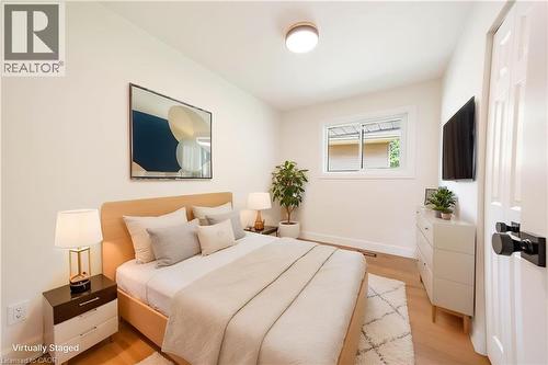 Light-filled room featuring wood-finish flooring, white trim, a modern ceiling light fixture, and a window with white framing - 22 Charlotte Crescent, Kitchener, ON 