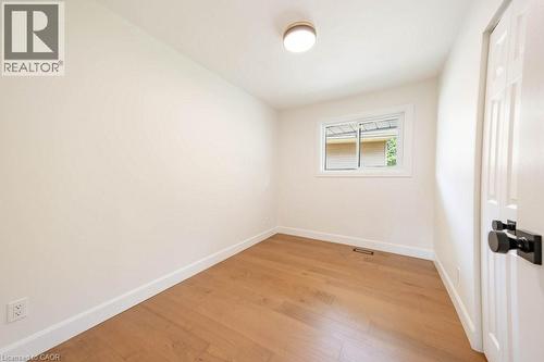 Room featuring wood-finish flooring, white baseboards, and neutral wall paint - 22 Charlotte Crescent, Kitchener, ON 