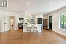 Open-concept living space featuring wood-finish flooring, recessed lighting, a kitchen island with seating, a black appliance suite, and a built-in entry bench with shelving - 22 Charlotte Crescent, Kitchener, ON 