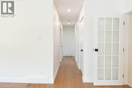 Bright hallway with wood-finish flooring, white walls, recessed lighting, and a white French door with frosted glass panels and a black doorknob - 22 Charlotte Crescent, Kitchener, ON 