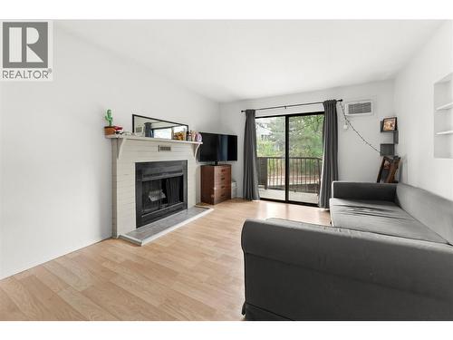 Bright & inviting living room featuring updated flooring, cozy fireplace, and large sliding doors leading to a private balcony with peaceful views and great natural light. - 555 Dalgleish Drive Unit# 412, Kamloops, BC - Indoor Photo Showing Living Room With Fireplace