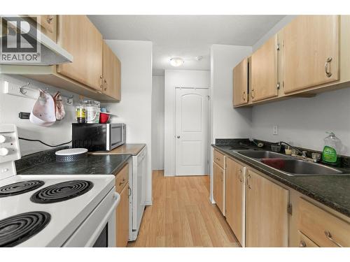 Efficient galley-style kitchen featuring ample cabinetry, generous counter space, and a practical layout perfect for everyday living and meal preparation. - 555 Dalgleish Drive Unit# 412, Kamloops, BC - Indoor Photo Showing Kitchen With Double Sink