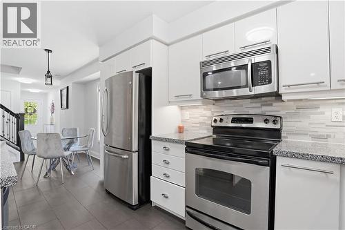 Modern kitchen featuring white cabinetry, stainless steel appliances, granite countertops, and a mosaic tile backsplash - 7 Upper Mercer Street Unit# G30, Kitchener, ON - Indoor Photo Showing Kitchen With Stainless Steel Kitchen With Upgraded Kitchen