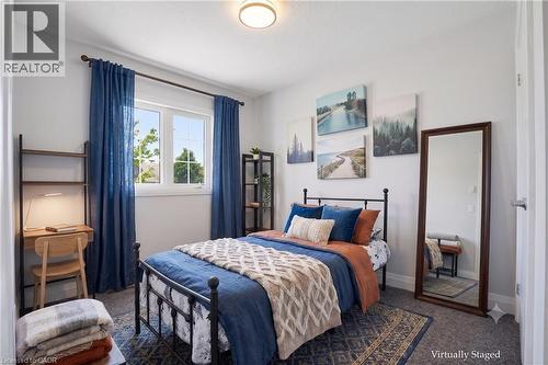 Virtually staged bright second bedroom featuring a large window, neutral wall paint, and gray carpeting - 7 Upper Mercer Street Unit# G30, Kitchener, ON - Indoor Photo Showing Bedroom