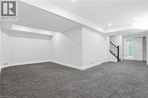 Spacious lower-level area featuring gray carpeting, white walls, recessed lighting, a staircase with dark banister, and a full bathroom with glass-enclosed shower - 7 Upper Mercer Street Unit# G30, Kitchener, ON - Indoor Photo Showing Other Room