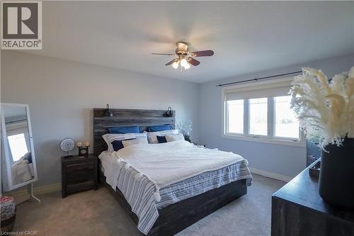 Carpeted bedroom featuring light blue walls, a contemporary ceiling fan, and a triple window with roller shades - 365 Poldon Drive, Norwich, ON 