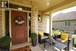 Covered front porch featuring a brick exterior and a brown front door with sidelights - 
