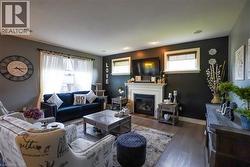 Living area featuring wood-finish flooring, a white mantel fireplace, and recessed ceiling lighting - 